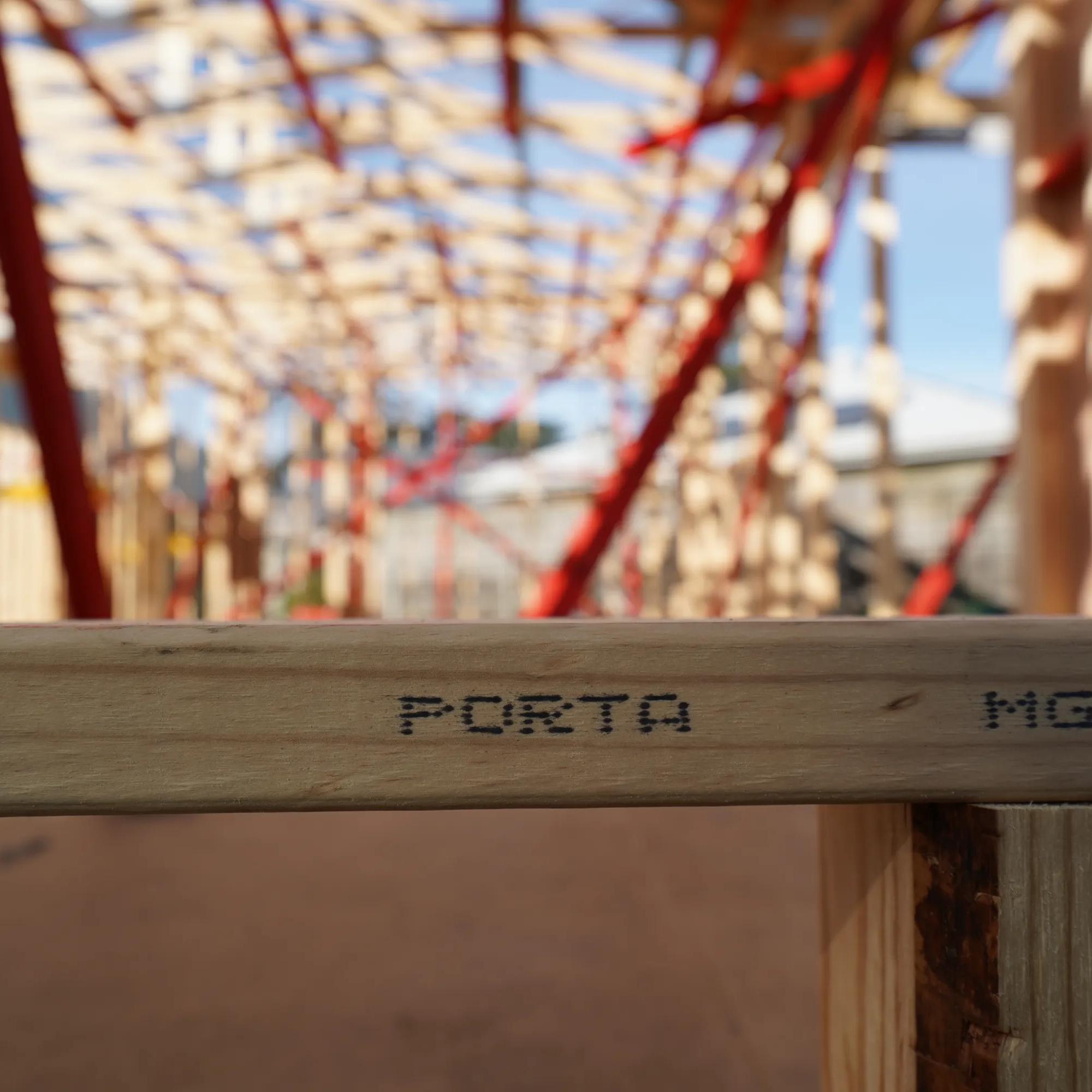 Porta timber beam marked PORTA within a sunlit timber construction frame