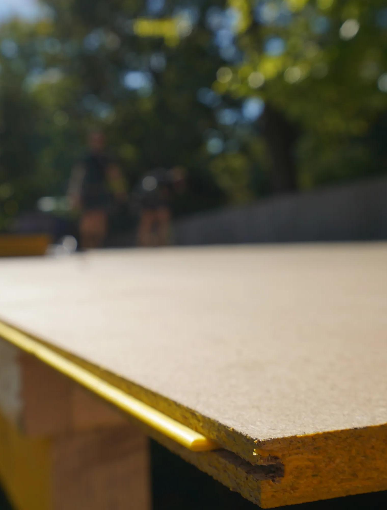Close-up of a timber board edge with a yellow trim outdoors