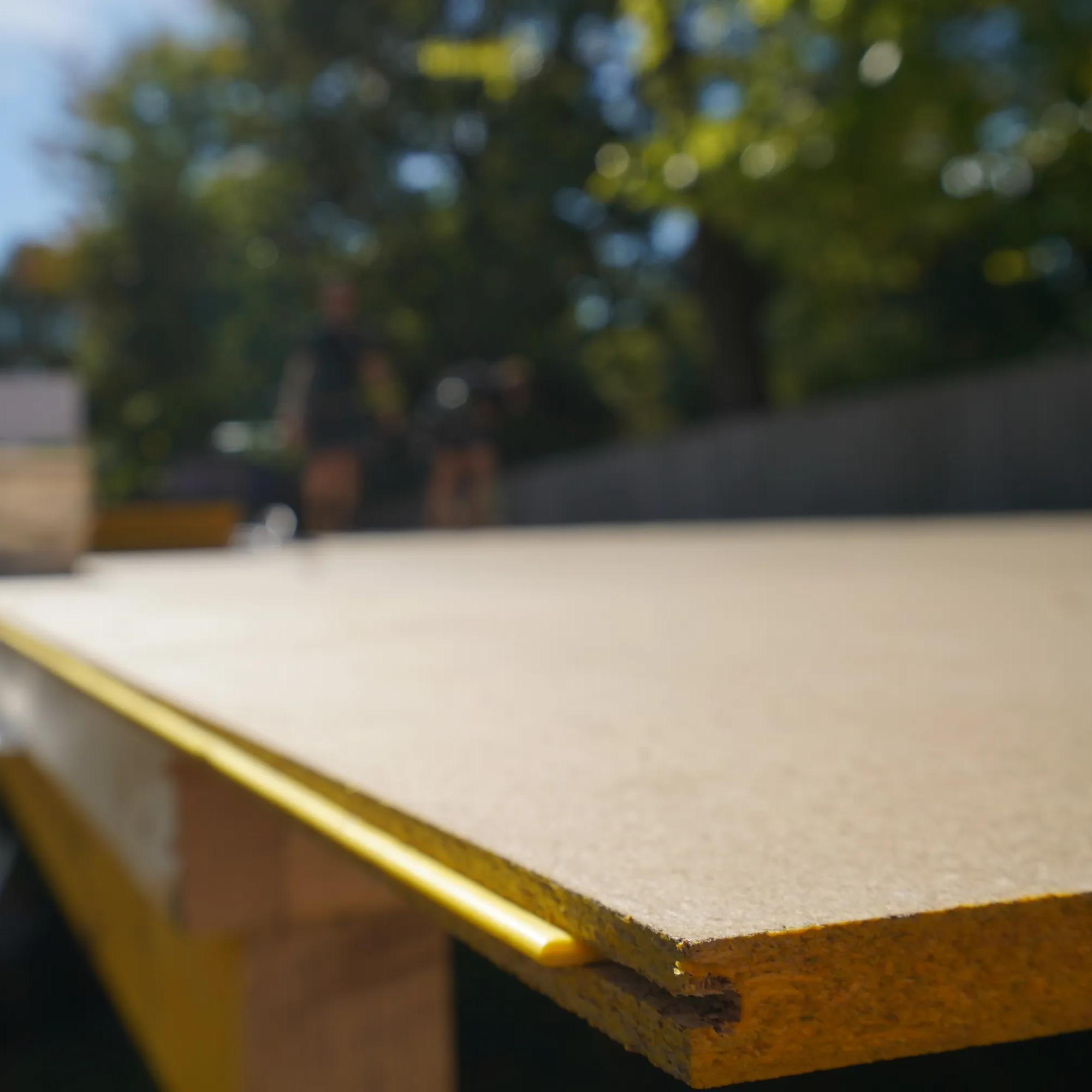 Close-up of a timber board edge with a yellow trim outdoors