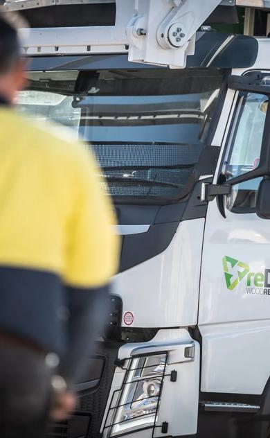 Hi-vis worker standing in front of reDirect Wood Recycling truck cab.