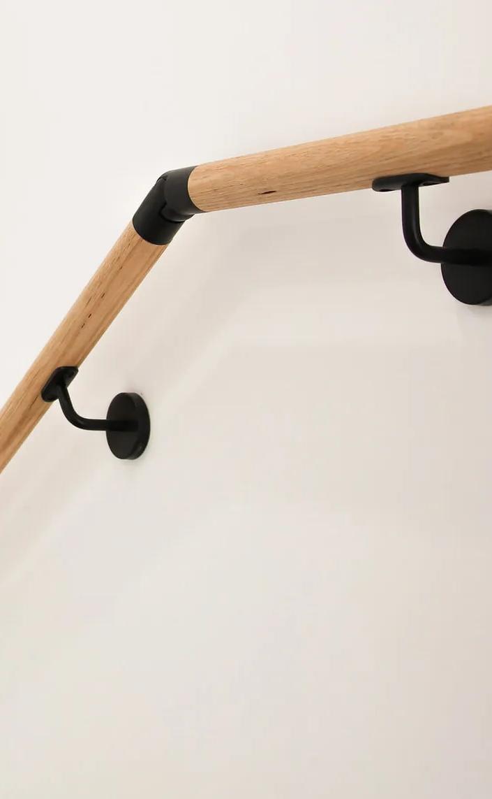 A wooden staircase handrailing next to a white wall