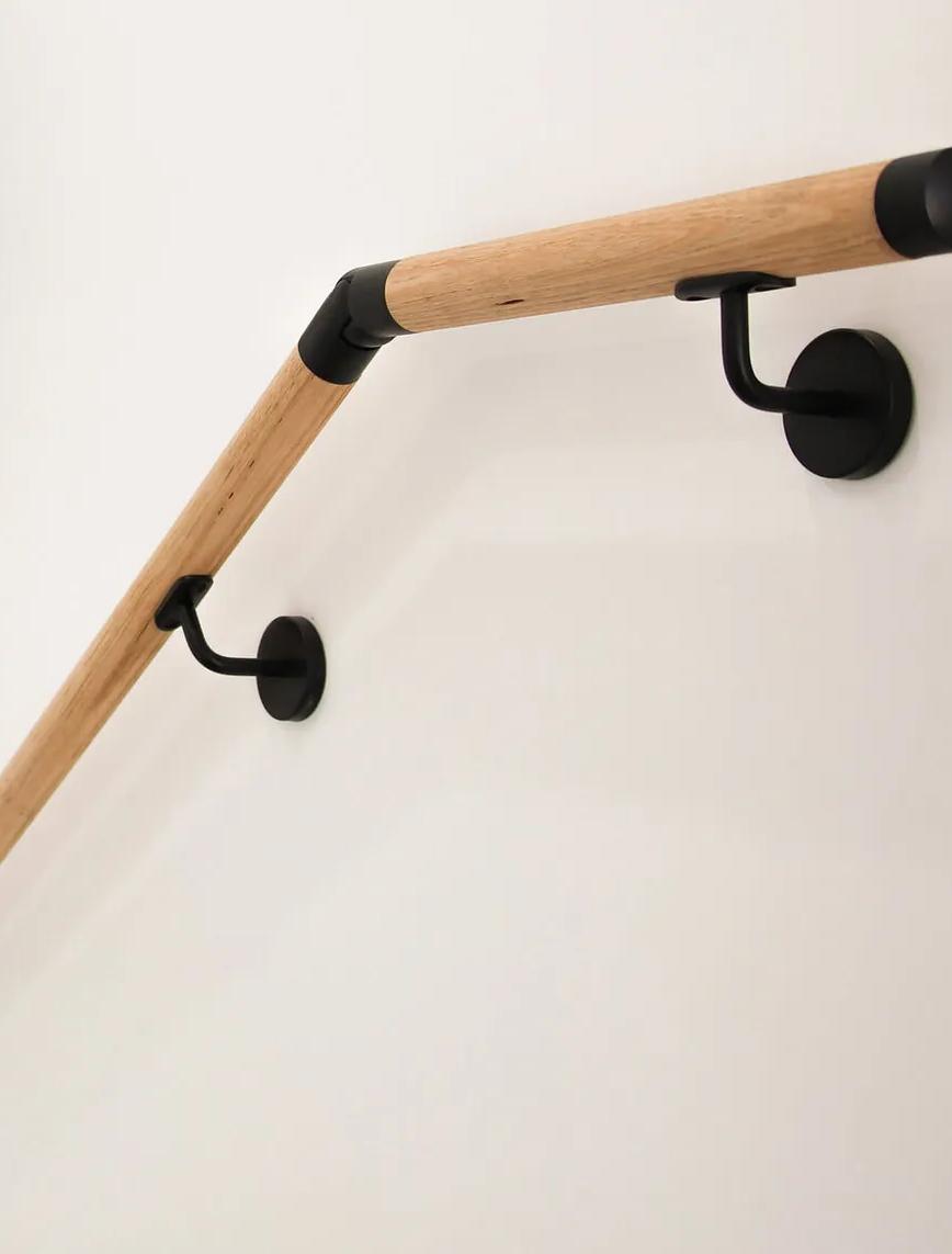 A wooden staircase handrailing next to a white wall