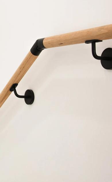 A wooden staircase handrailing next to a white wall