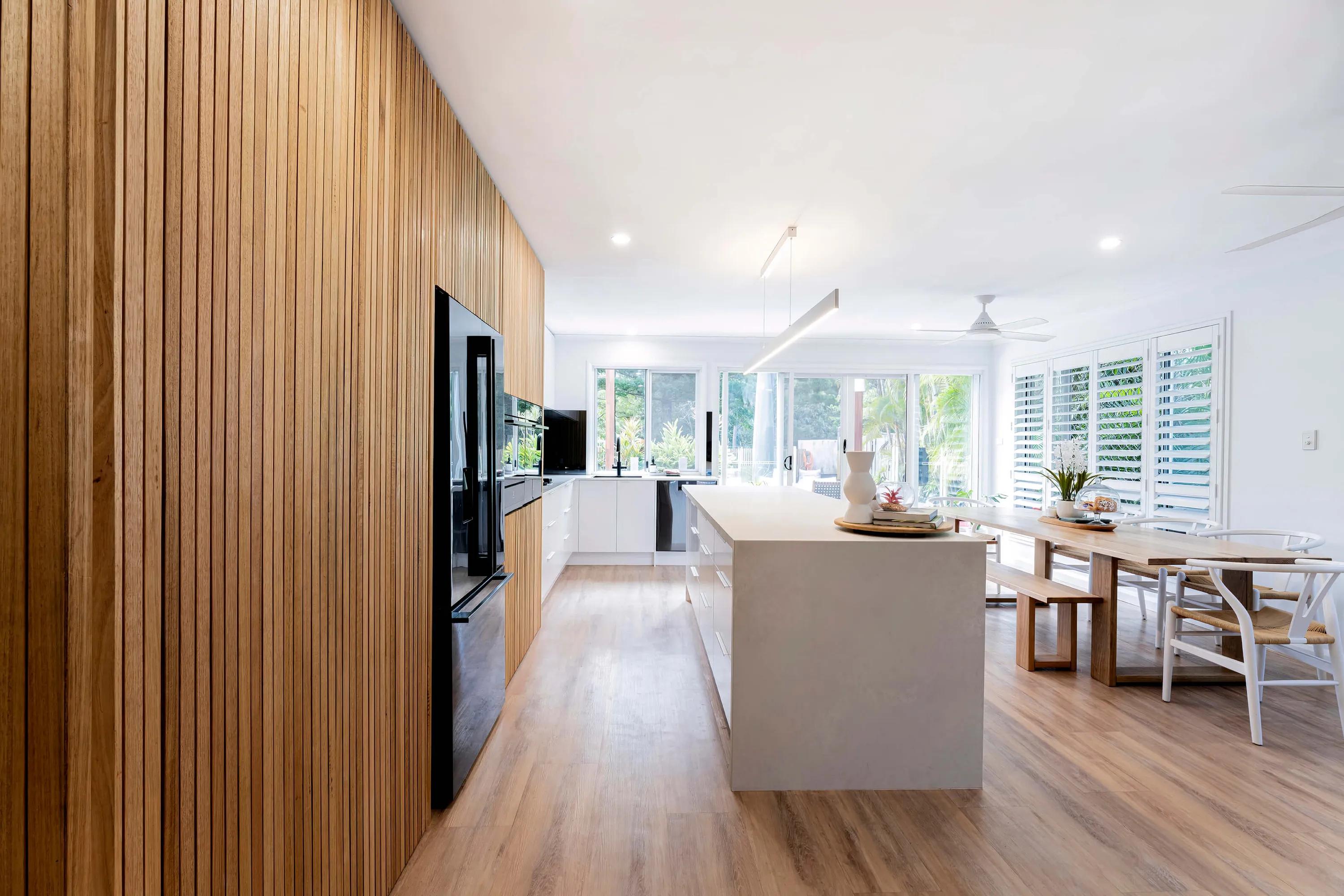 Large open room with white walls, wooden paneling, and modern appliances