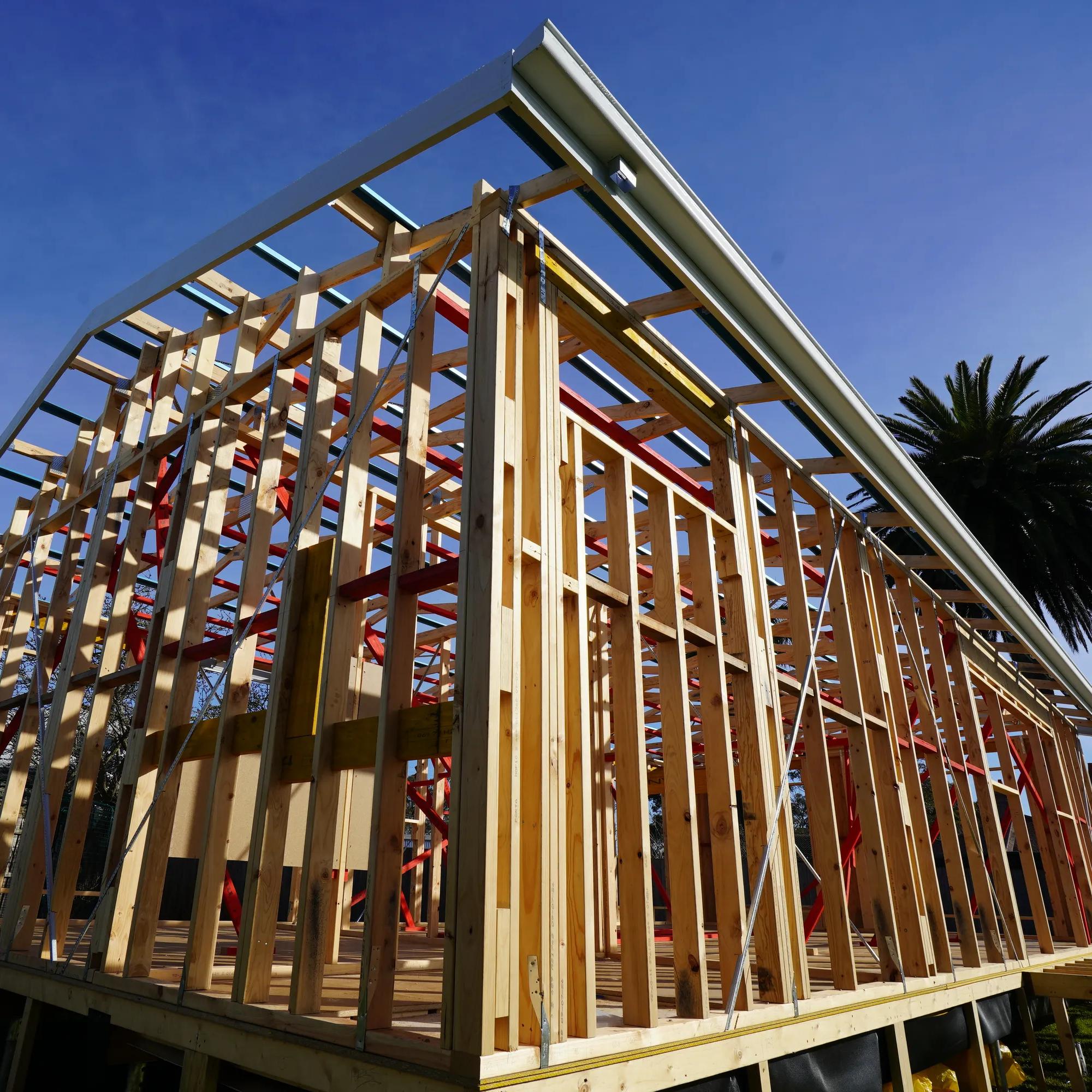 Timber-framed house under construction with roof framing and exposed wall studs
