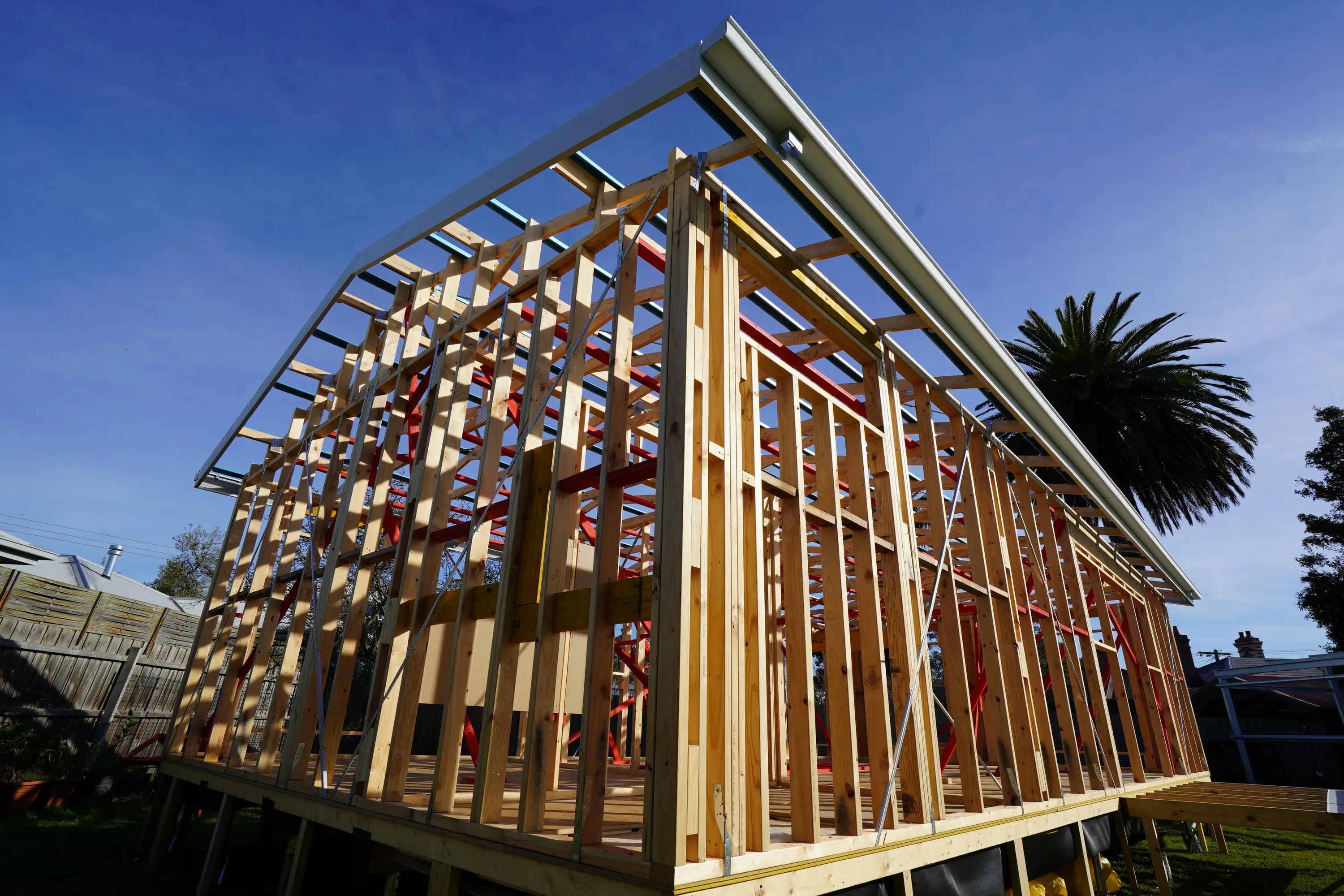 Timber-framed house under construction with roof framing and exposed wall studs