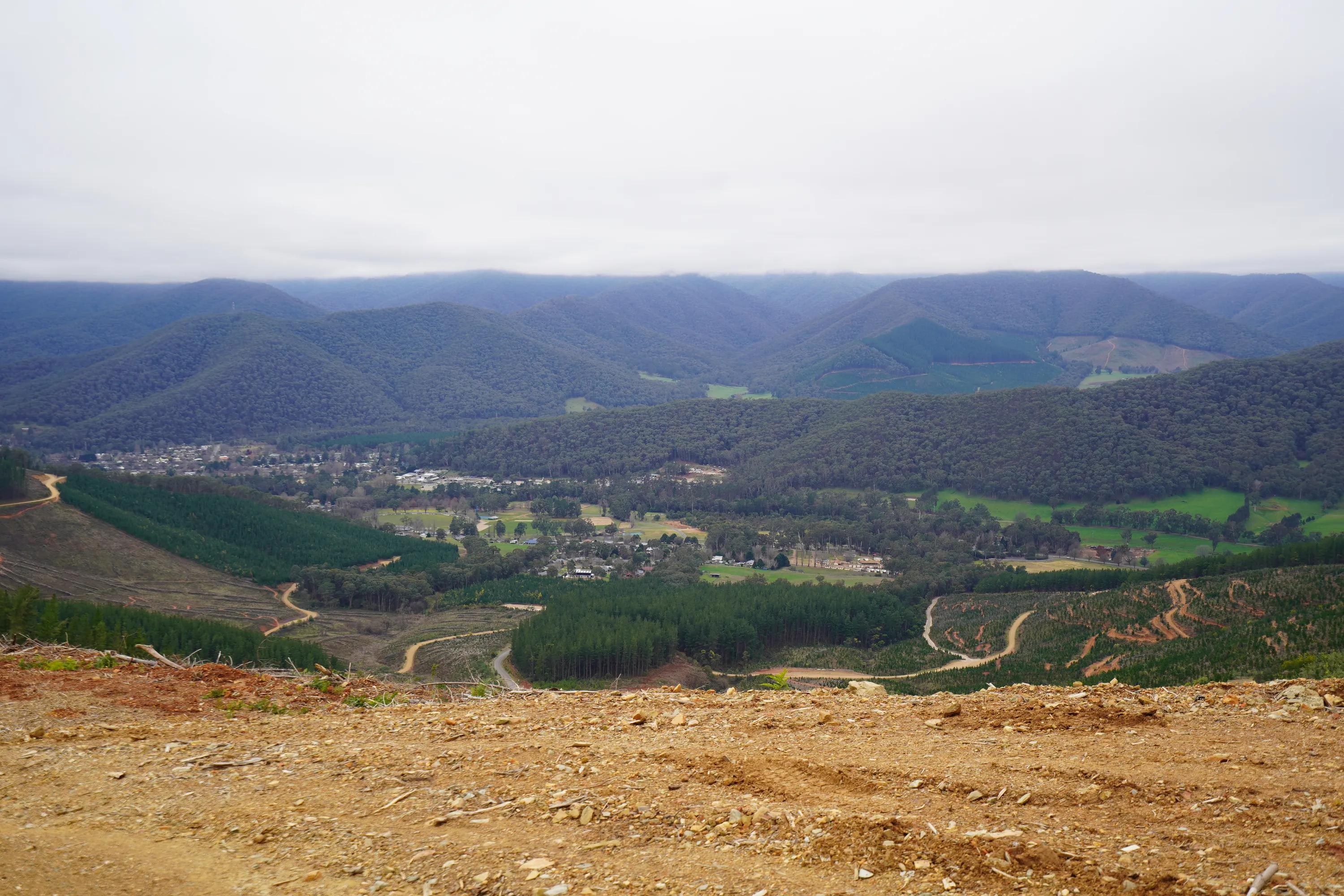 Panoramic view of forested hills, farmland and a rural settlement from a cleared hillside