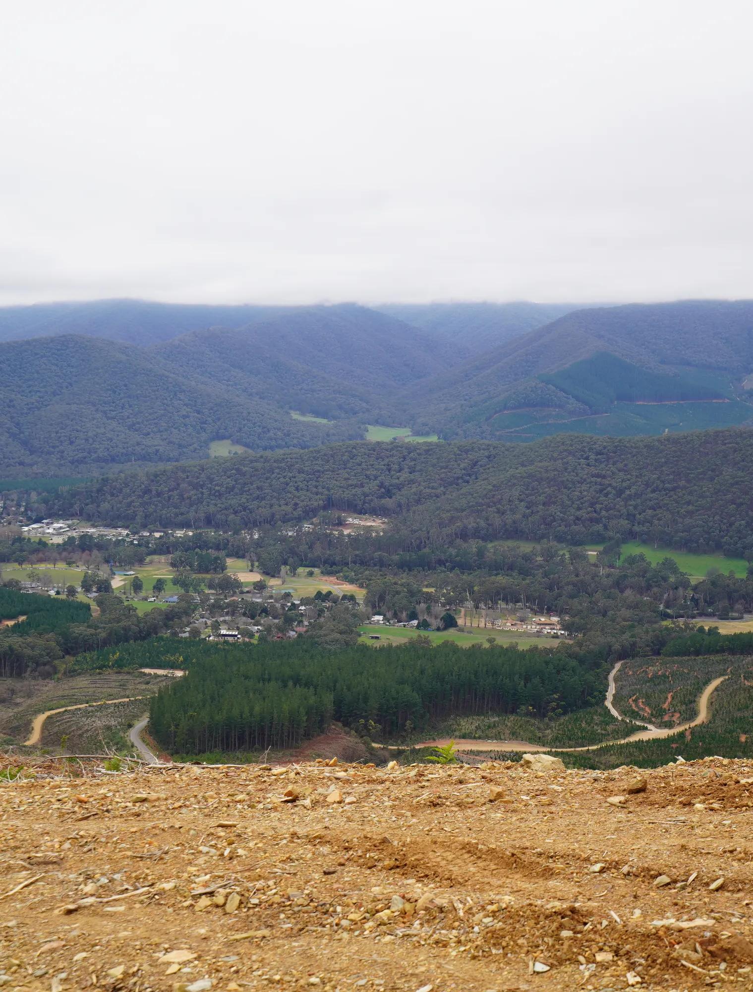 Panoramic view of forested hills, farmland and a rural settlement from a cleared hillside