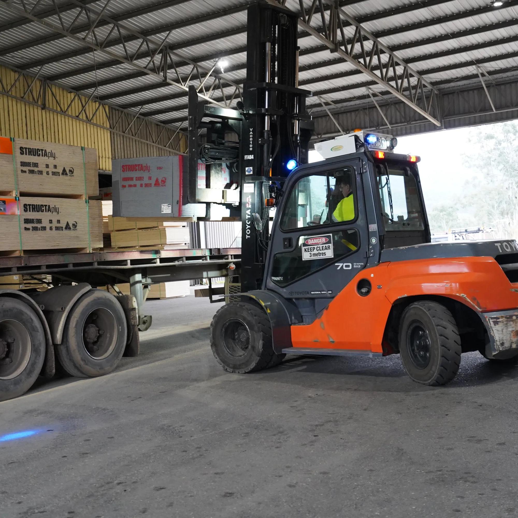 Forklift loading STRUCTAply sheets onto a truck inside a warehouse