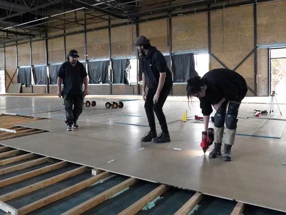 Three men installing STRUCTAflor in an indoor setting