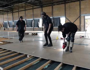 Three men installing STRUCTAflor in an indoor setting