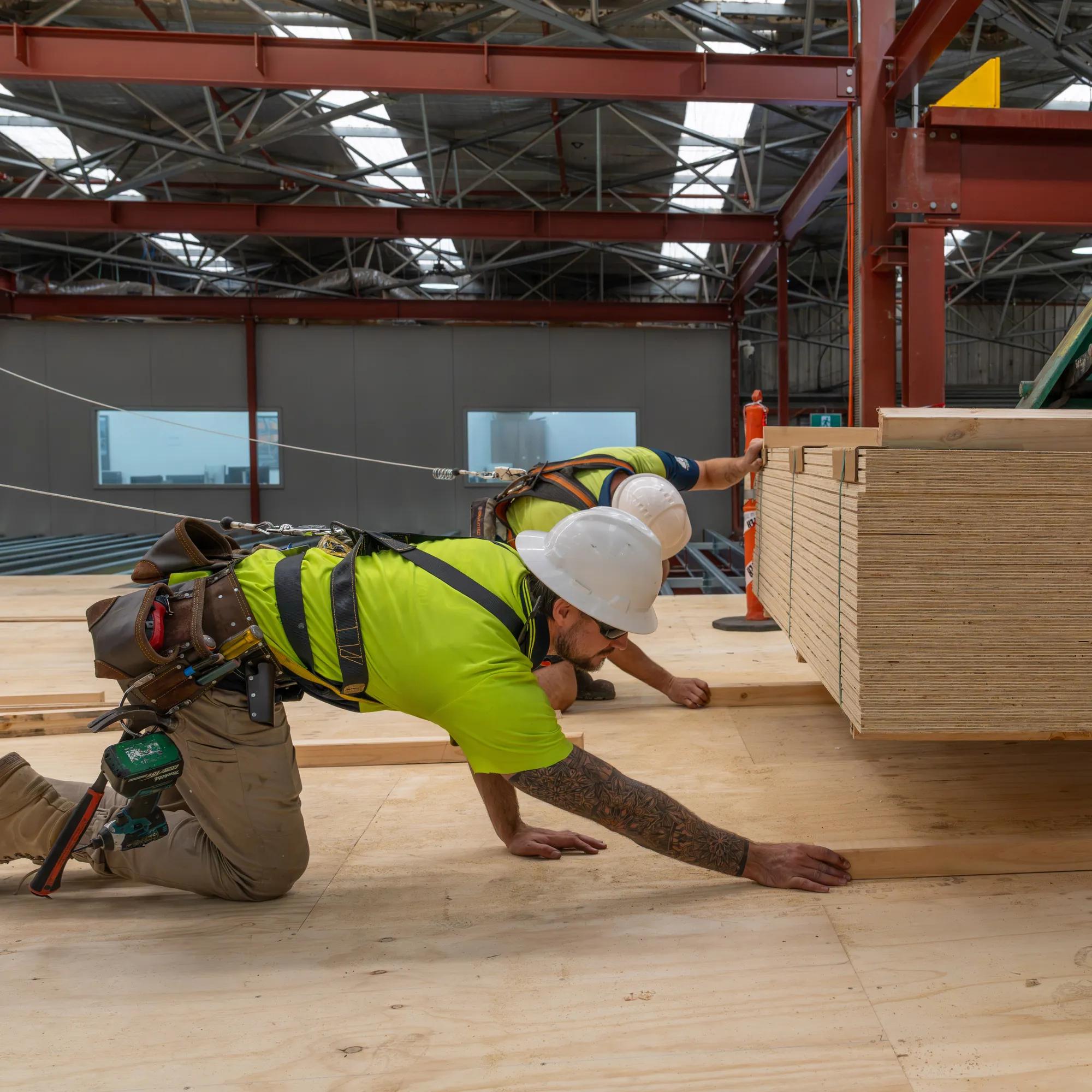 Worker installing STRUCTAply plywood flooring in an industrial warehouse