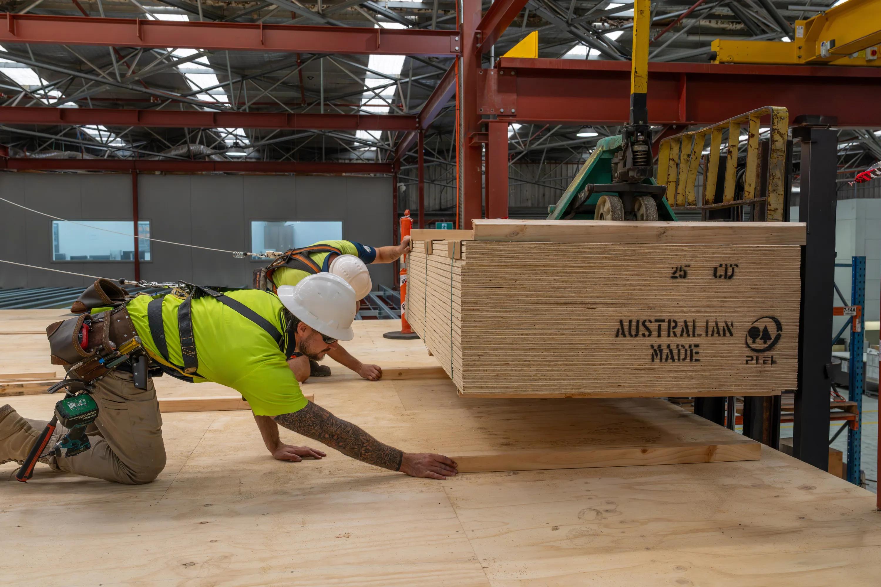 Worker installing STRUCTAply plywood flooring in an industrial warehouse