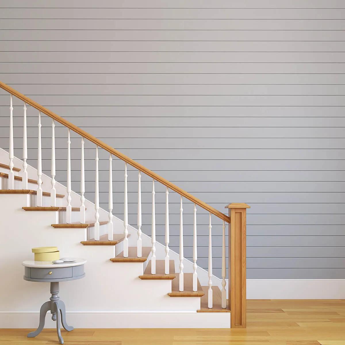 White staircase with wooden banister next to blue wall