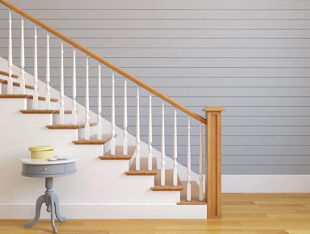 White staircase with wooden banister next to blue wall