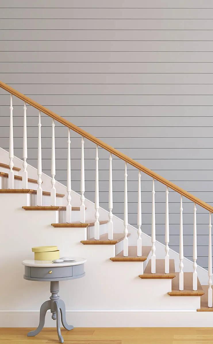 White staircase with wooden banister next to blue wall