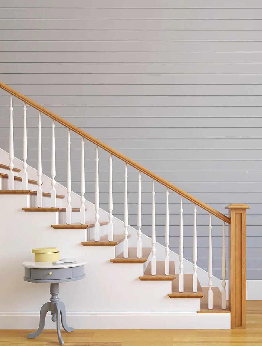 White staircase with wooden banister next to blue wall