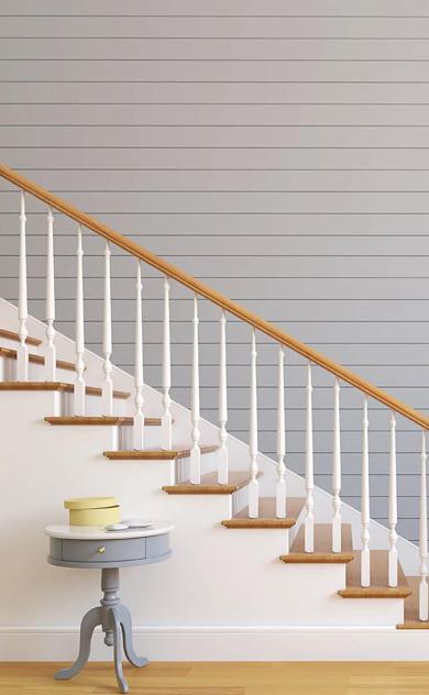 White staircase with wooden banister next to blue wall