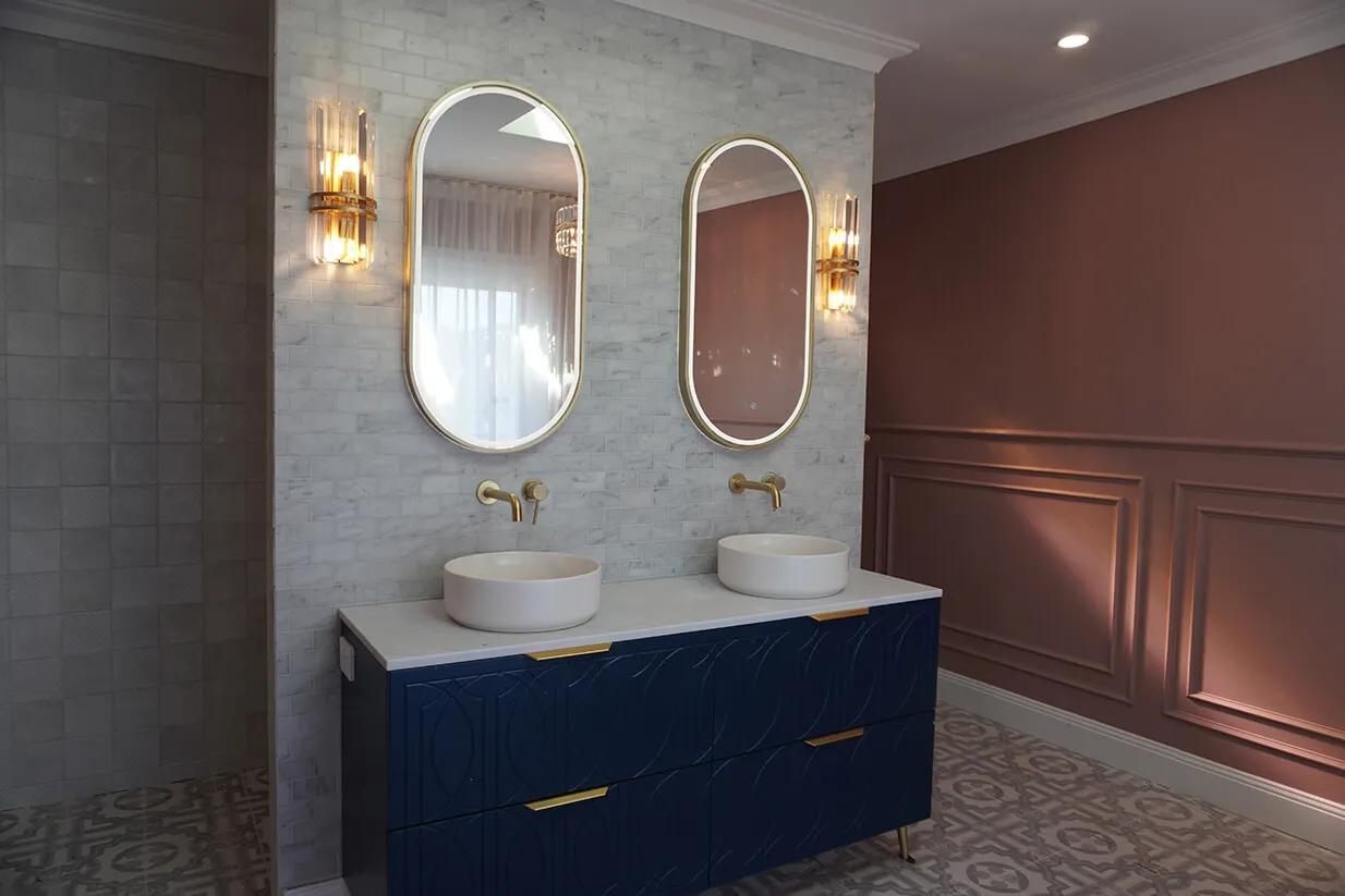 This is a bathroom. The bathroom has a dark blue sink countertop. There are two sinks in the image. The walls are tiled