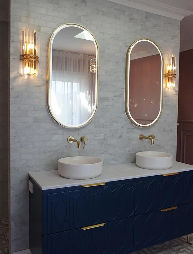 This is a bathroom. The bathroom has a dark blue sink countertop. There are two sinks in the image. The walls are tiled
