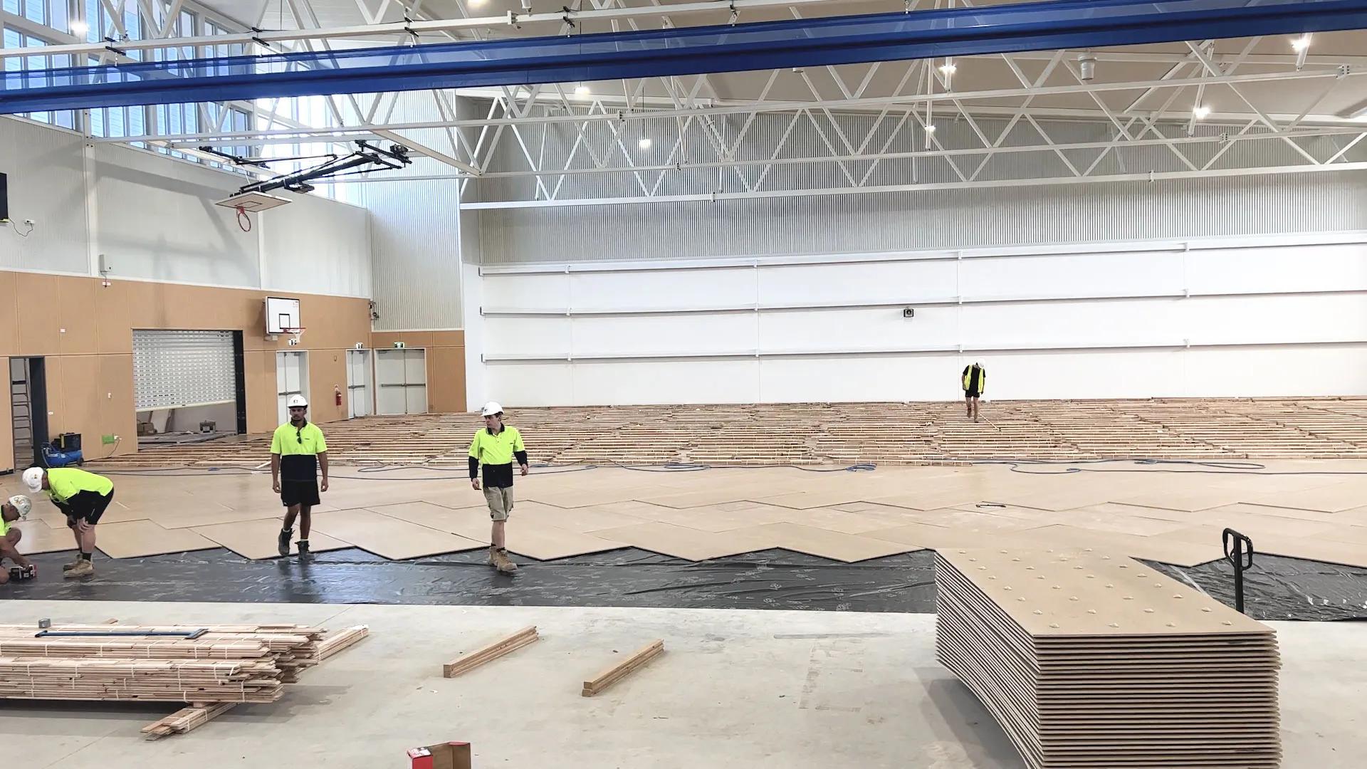 Several workers in the gymnasium,STRUCTApanel Smooth flooring installation in progress