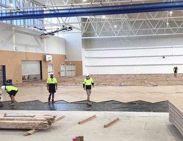 Several workers in the gymnasium,STRUCTApanel Smooth flooring installation in progress