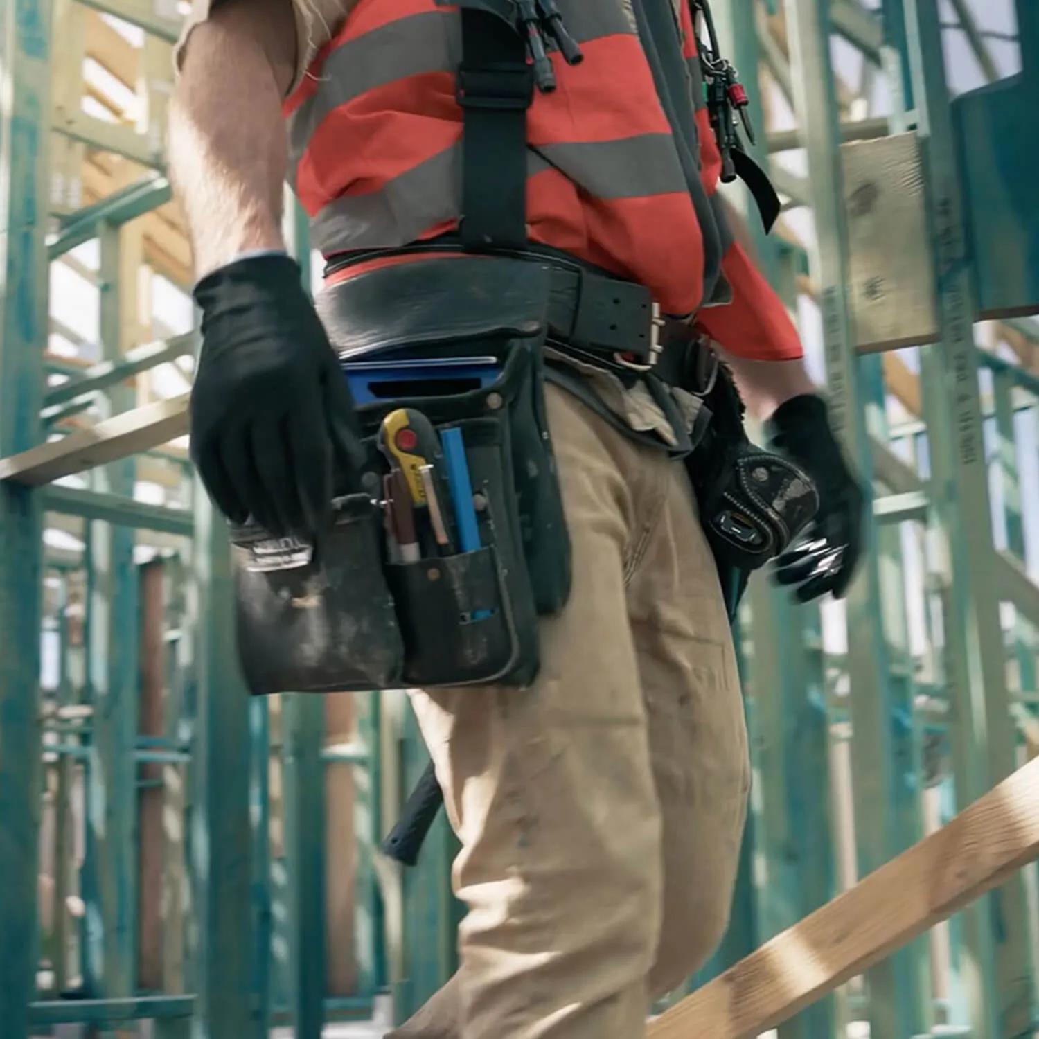 Worker in orange vest with tools building with STRUCTAframe