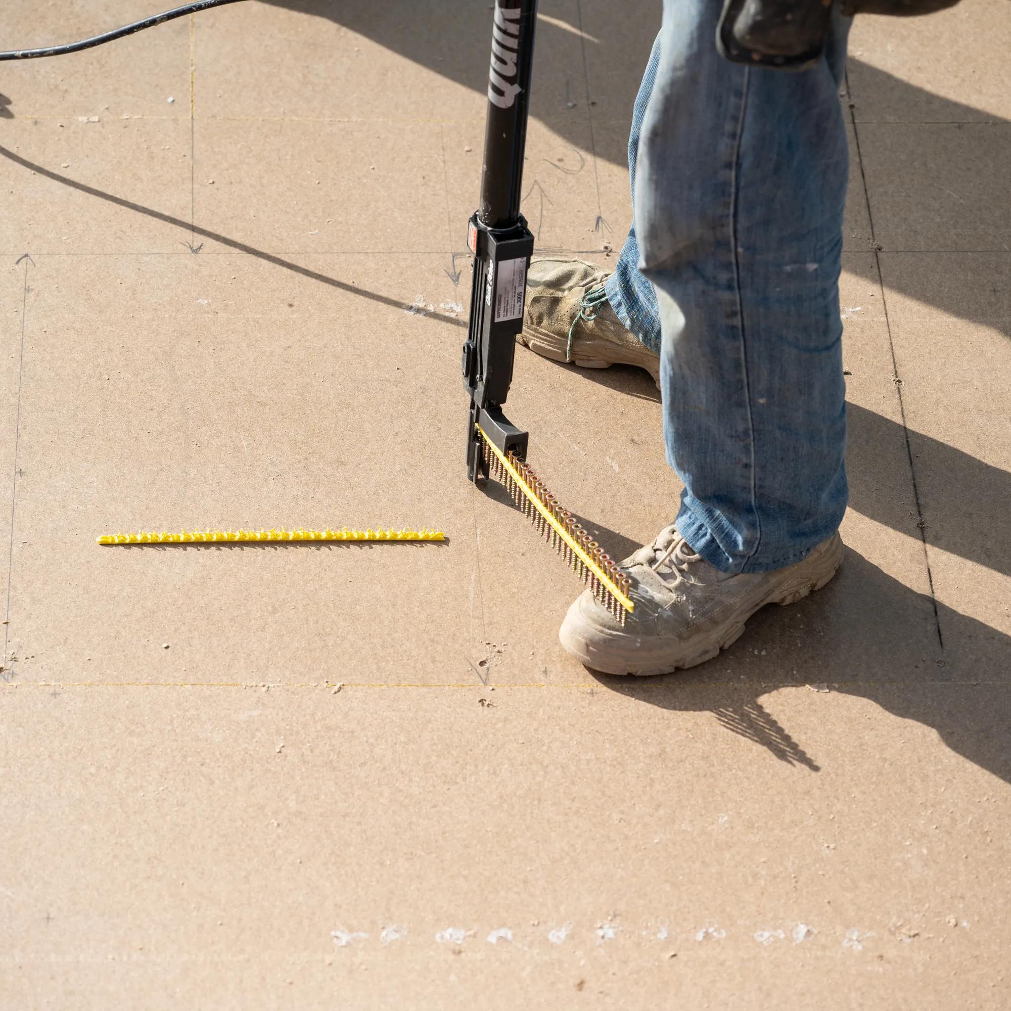 Person using a Porta tool to sweep a yellow bristle strip across a concrete surface