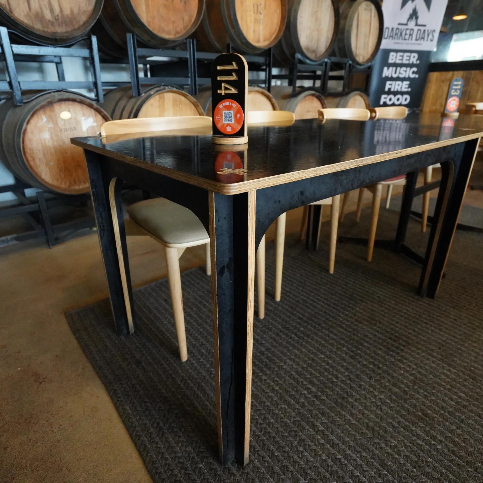 STRUCTAply table with stools in a bar interior featuring wooden barrels