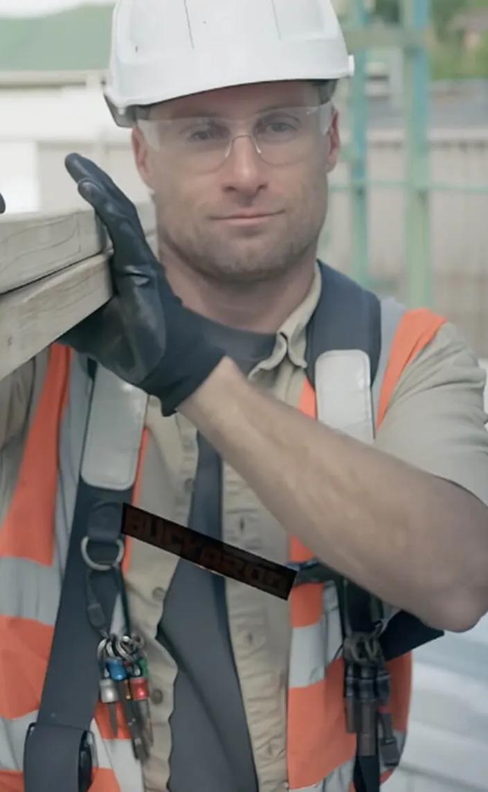 Worker in orange vest with tools building with STRUCTAframe