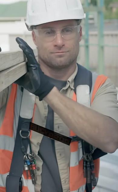 Worker in orange vest with tools building with STRUCTAframe