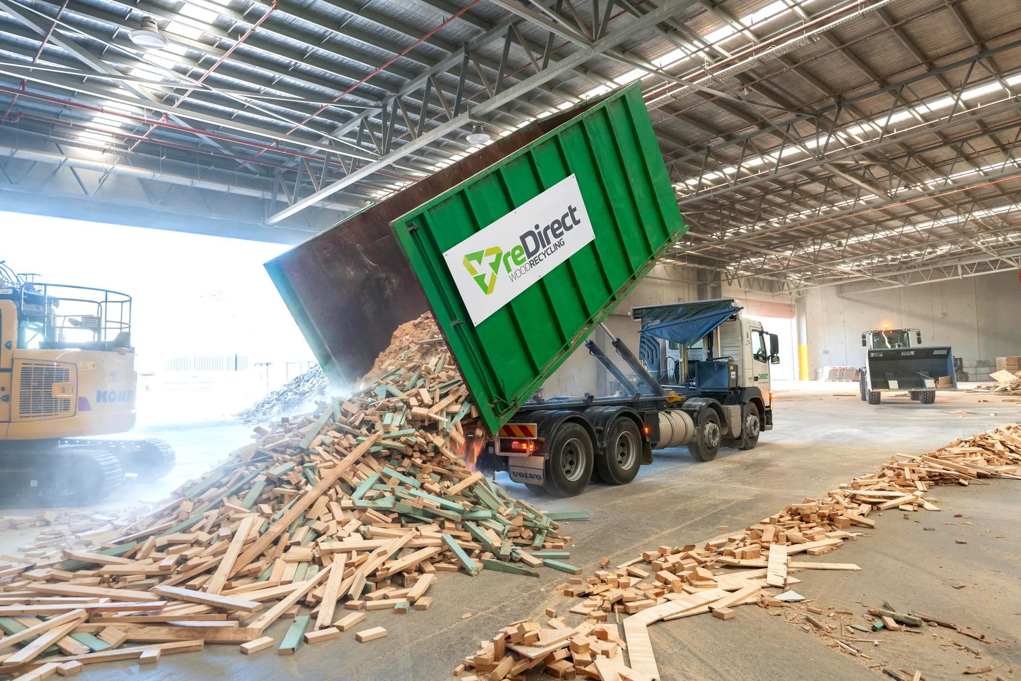 reDirect Wood Recycling truck tipping frame and truss timber waste in warehouse.