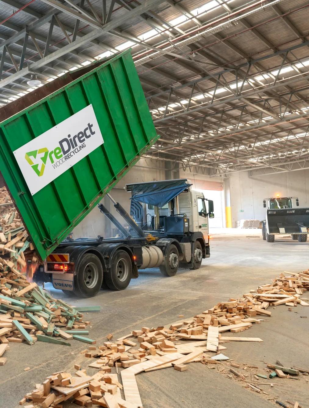 reDirect Wood Recycling truck tipping frame and truss timber waste in warehouse.