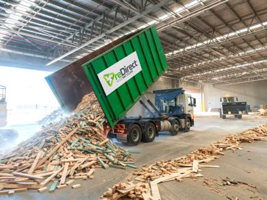 reDirect Wood Recycling truck tipping frame and truss timber waste in warehouse.