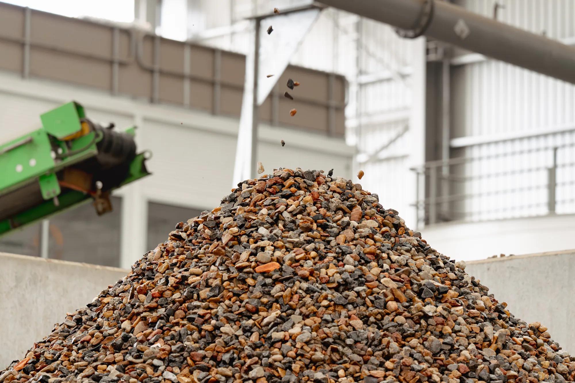 Large pile of recycled aggregate and stone at soil recycling facility.