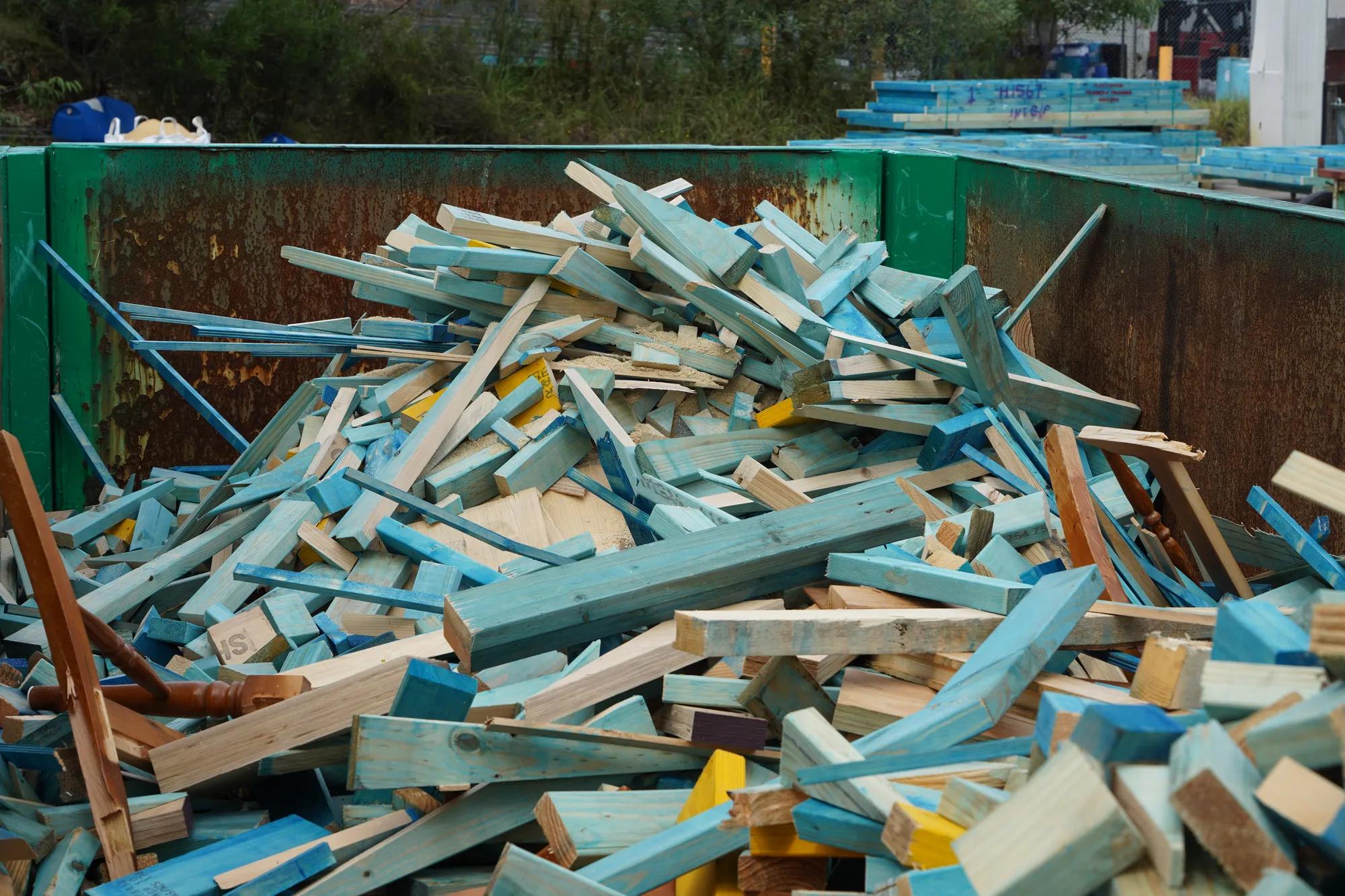 Broken timber frame and truss waste inside green reDirect recycling bin.