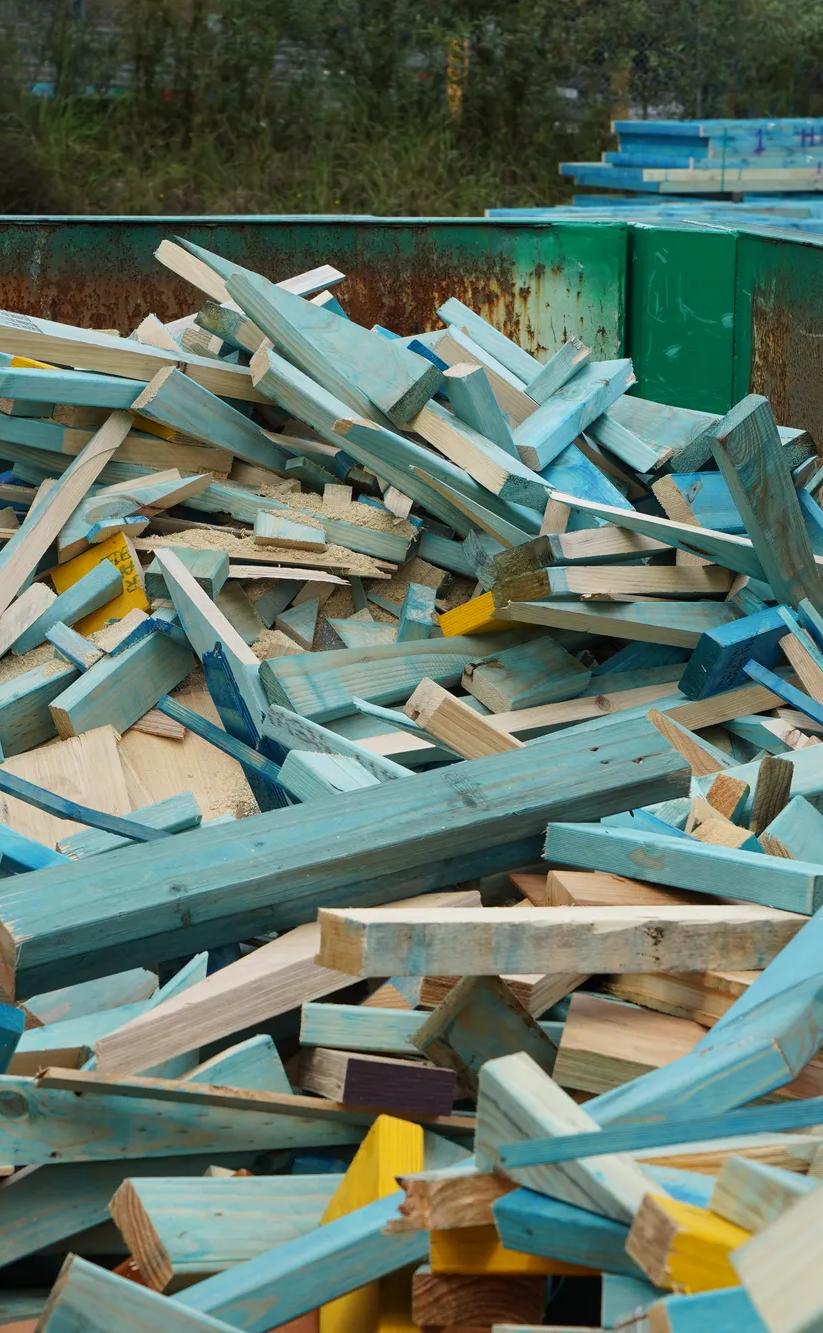 Broken timber frame and truss waste inside green reDirect recycling bin.