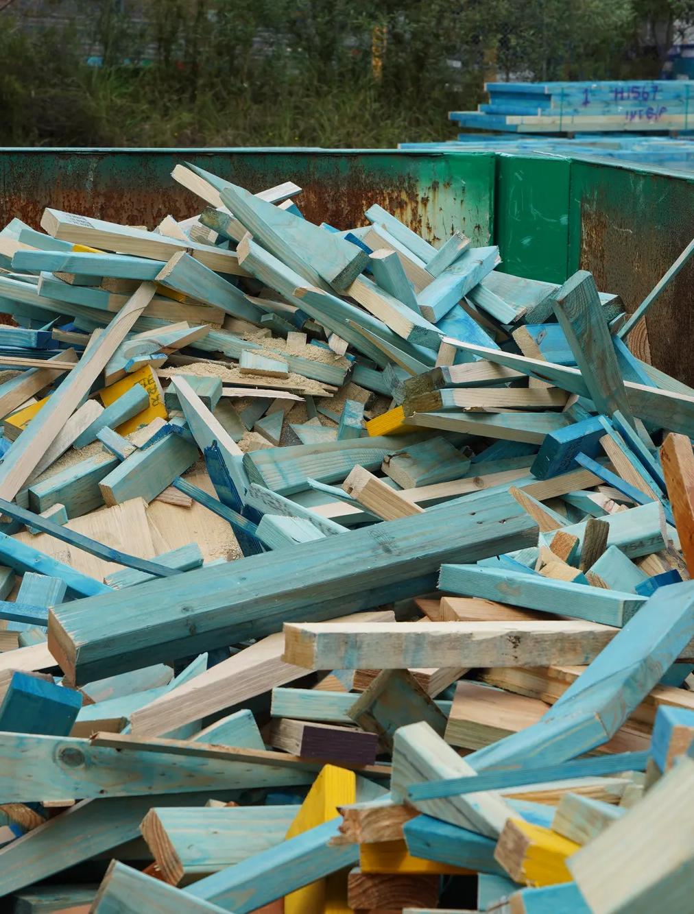 Broken timber frame and truss waste inside green reDirect recycling bin.