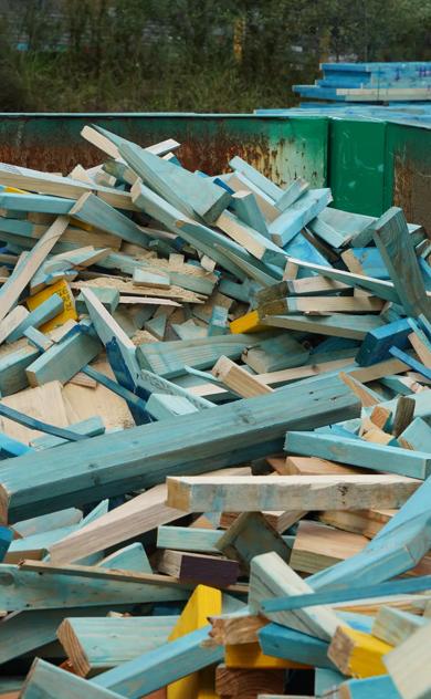 Broken timber frame and truss waste inside green reDirect recycling bin.
