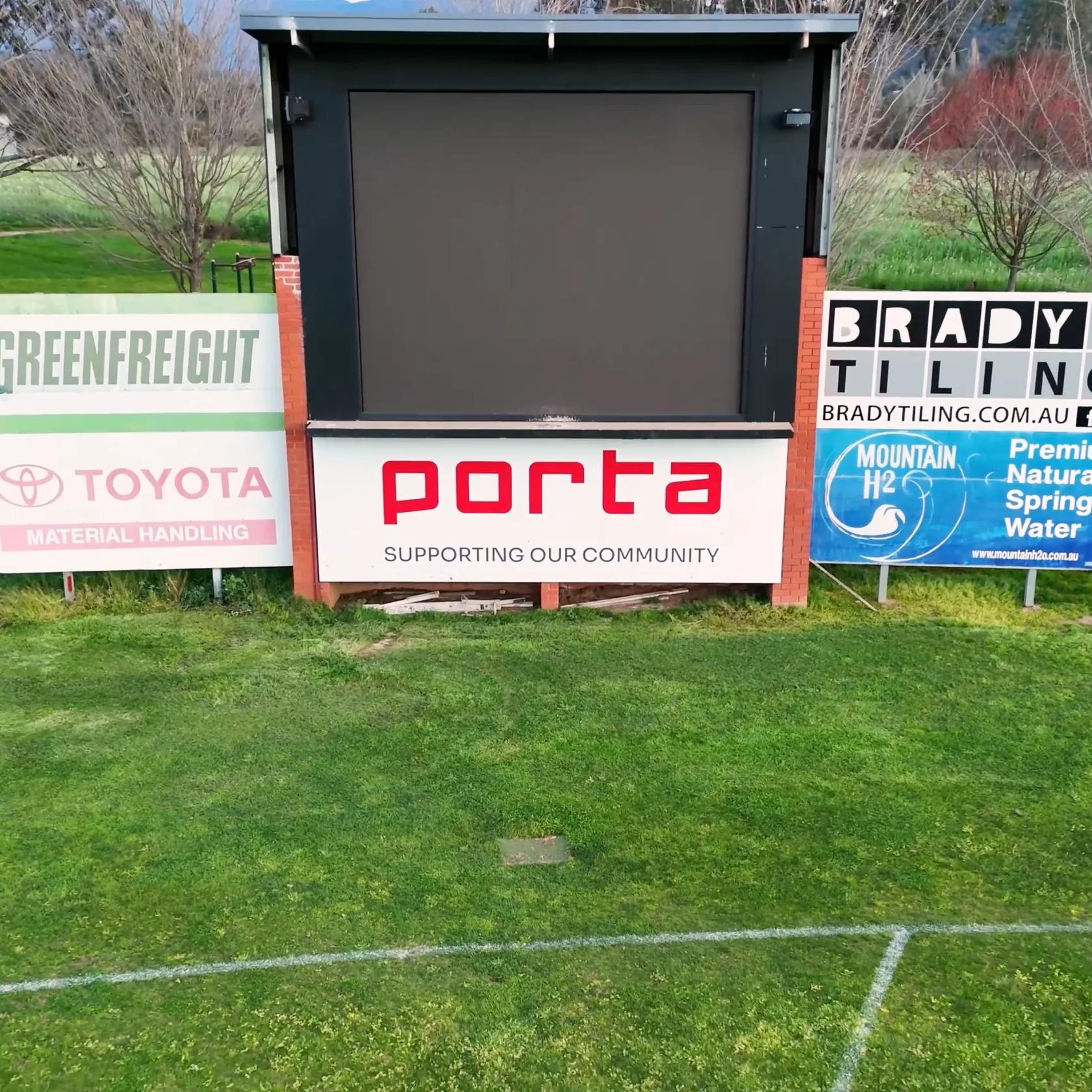 STRUCTAply shelter with Porta and community sponsor signage beside a sports field