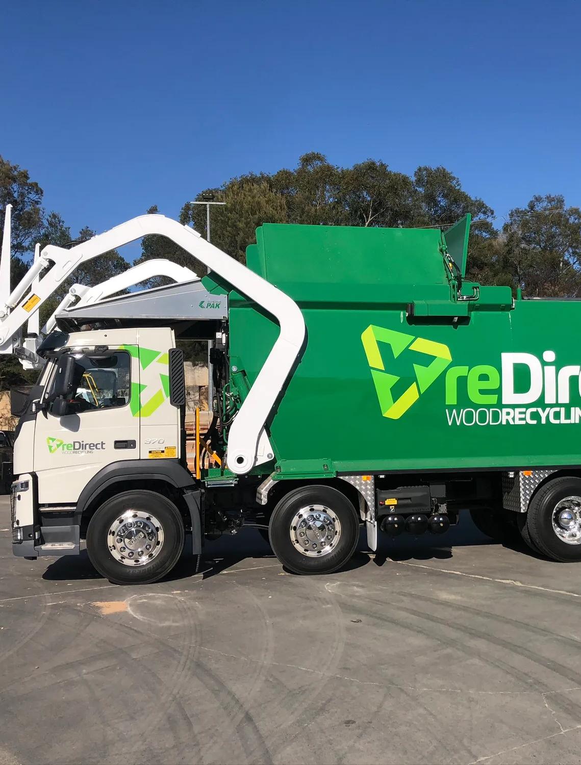 reDirect Wood Recycling green collection truck full side view outdoors.