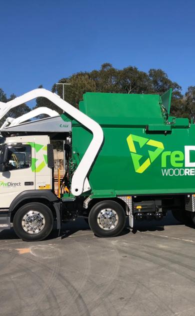 reDirect Wood Recycling green collection truck full side view outdoors.