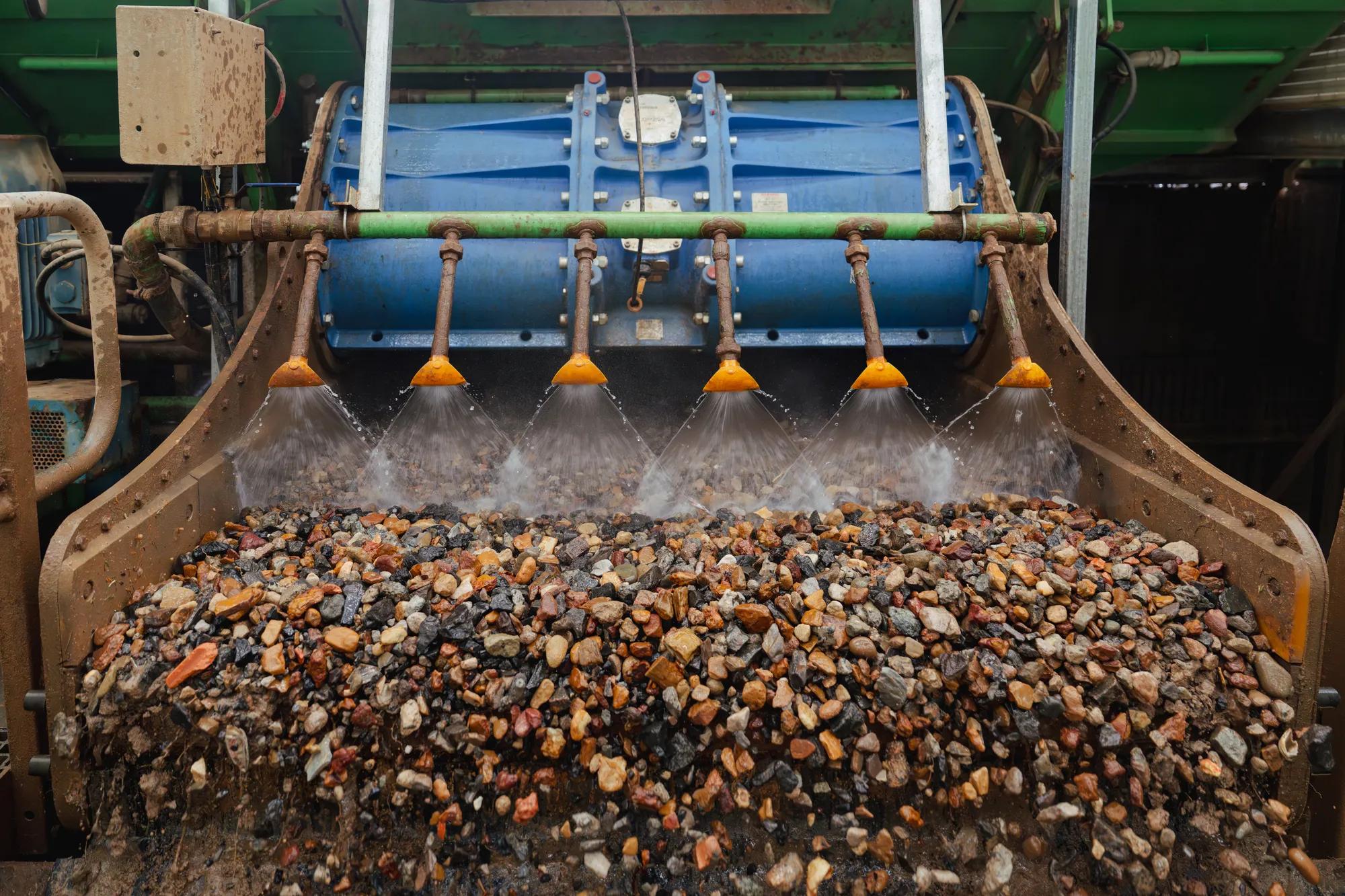 Pile of recycled aggregate gravel at processing facility with conveyor belt.