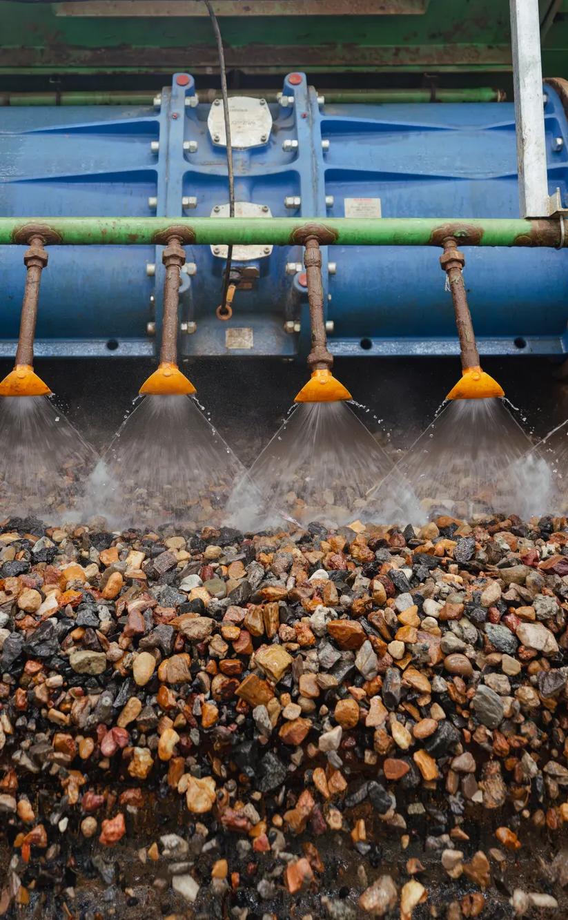 Pile of recycled aggregate gravel at processing facility with conveyor belt.