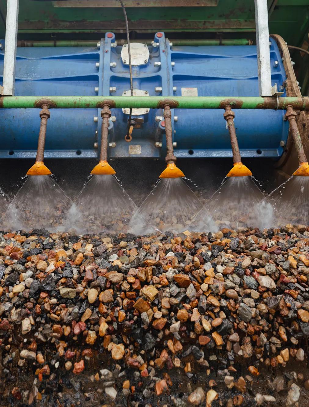 Pile of recycled aggregate gravel at processing facility with conveyor belt.