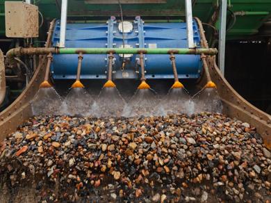 Pile of recycled aggregate gravel at processing facility with conveyor belt.