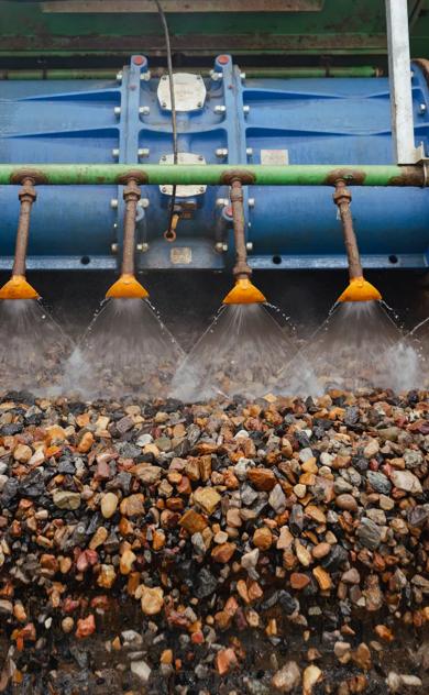 Pile of recycled aggregate gravel at processing facility with conveyor belt.