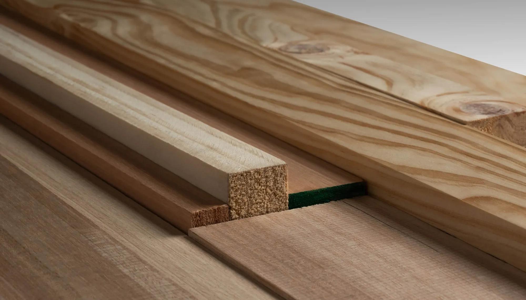 A collection of wooden planks stacked horizontally. These planks have visible wood grain patterns, and their ends show a smooth finish. The image focuses on the construction material aspect of the scene, emphasizing the quality of the wood, with close-up details showcasing the texture and color variations in the wood fibers