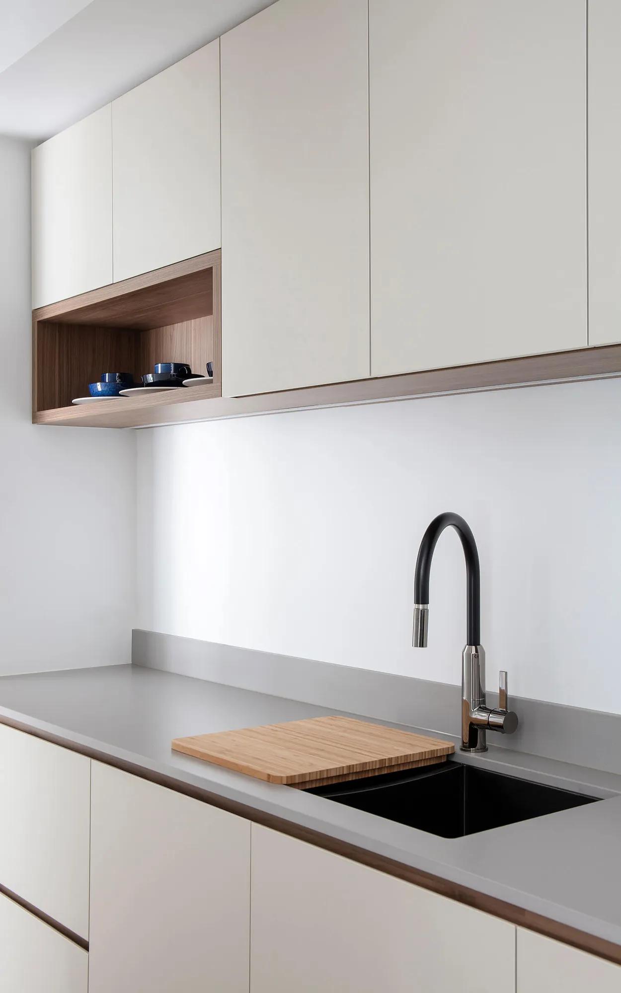 Large white kitchen cabinets, black countertop, silver faucet, wooden cutting board