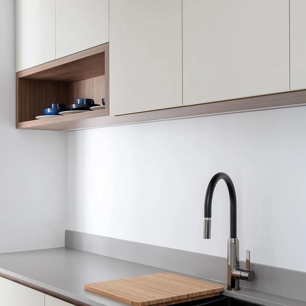 Large white kitchen cabinets, black countertop, silver faucet, wooden cutting board